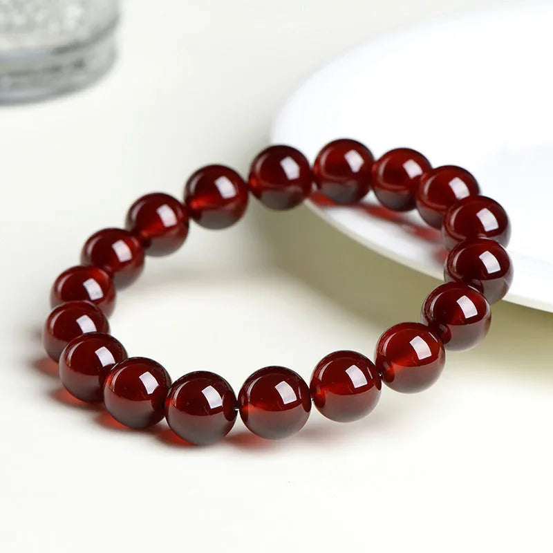 Natural Orange Red Garnet ball bracelet with a Ruyi charm on a white background