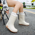 Women's solid colour PVC rain boots with non-slip soles in apricot, black, brown, and pink.