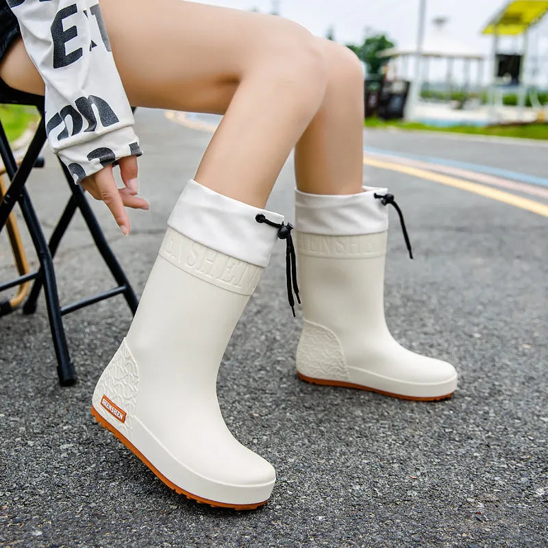 Women's solid colour PVC rain boots with non-slip soles in apricot, black, brown, and pink.