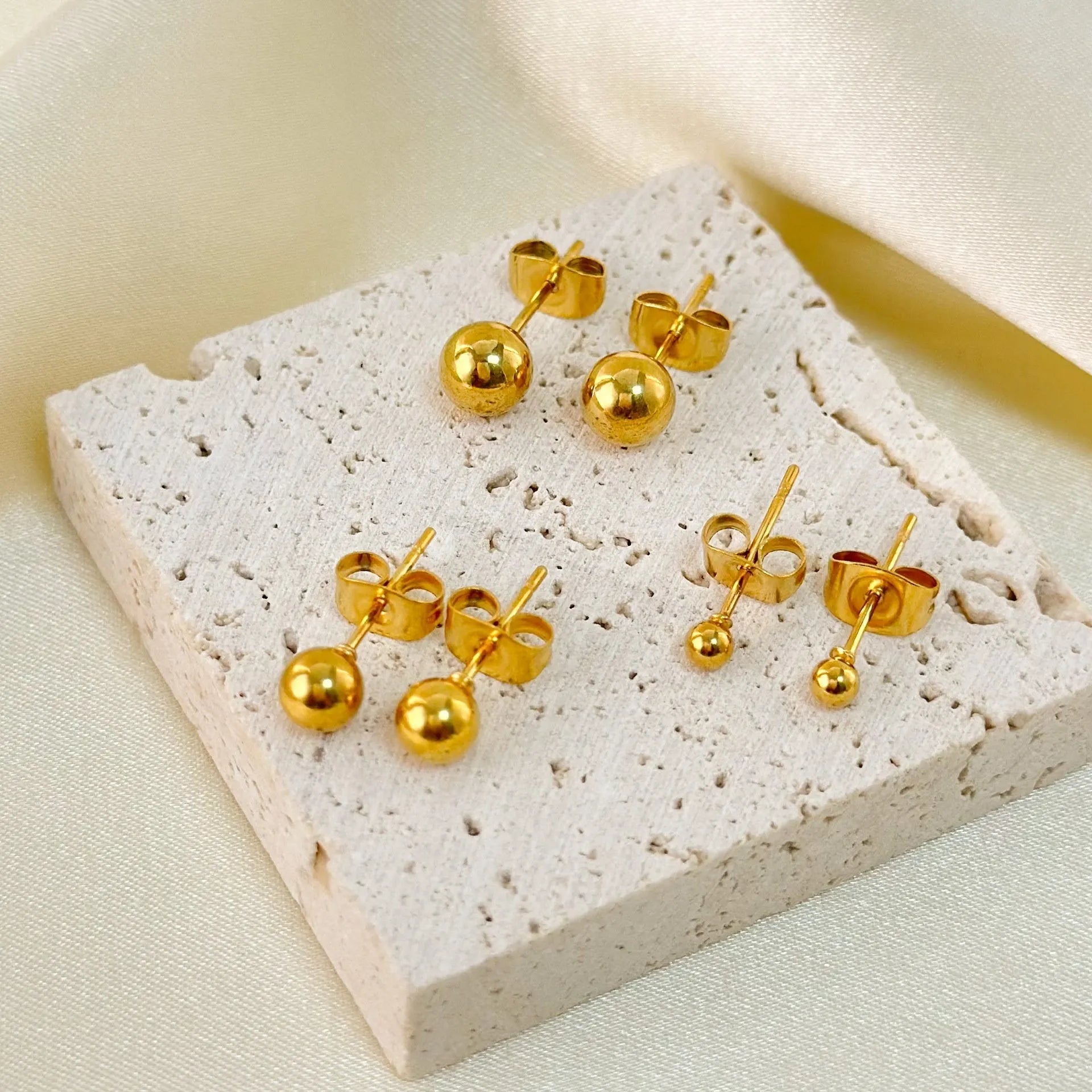 Gold and silver spherical ball stud earrings in 3mm, 4mm, 5mm, and 6mm sizes on a plain background.