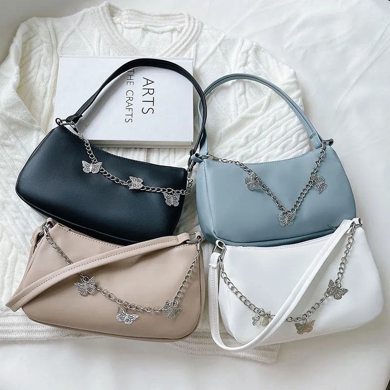 Women's black butterfly chain underarm bag with crossbody strap, showing structured square shape and retro style.
