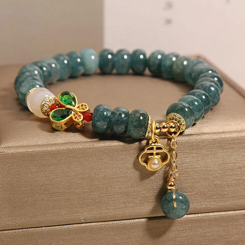 Close-up of a women's bracelet with blue water jade abacus beads, white agate, alloy inlay, and a butterfly clasp.