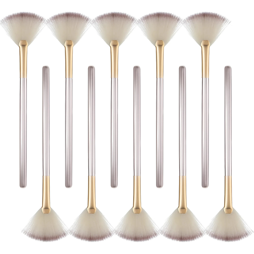 Ten champagne-coloured facial fan brushes with soft bristles and protective covers laid out.