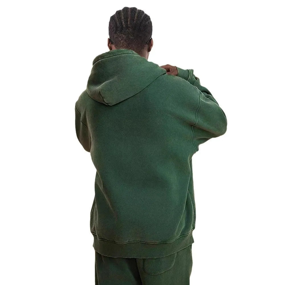 Man wearing a dark green fleece-lined hooded cardigan sweater with a double zipper.