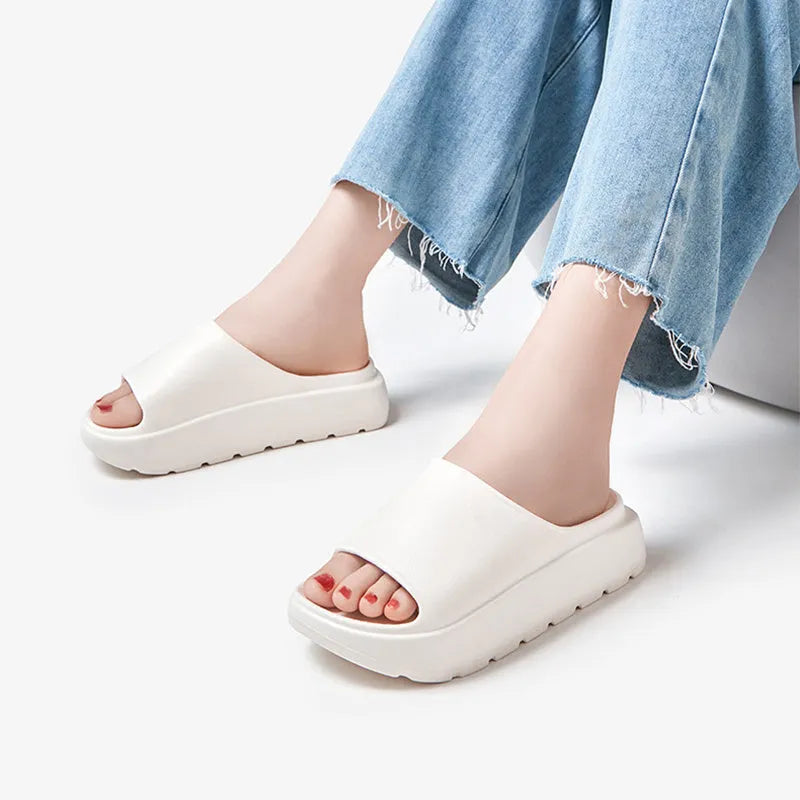 Women's thick-soled EVA beach slippers in beige, shown from the side on a sandy surface.