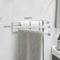Black folding towel rack mounted on a bathroom wall with towels hanging, showing its no-drill installation.