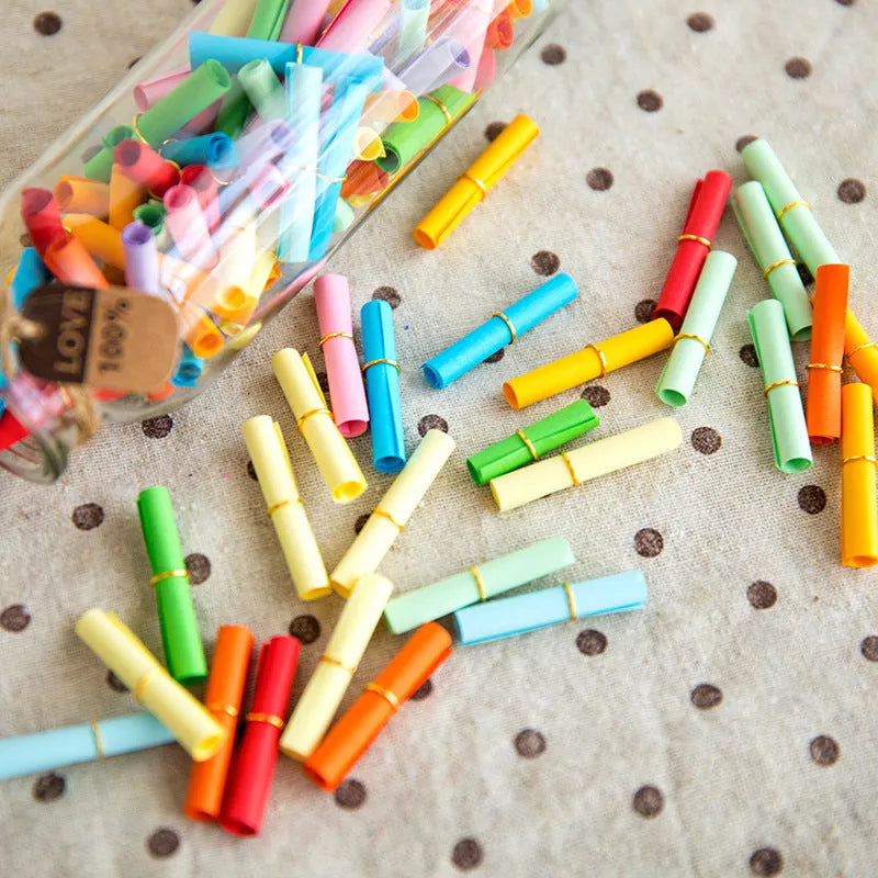Assortment of colourful mini paper scrolls with metal eyelets for drift bottle messages and crafts.