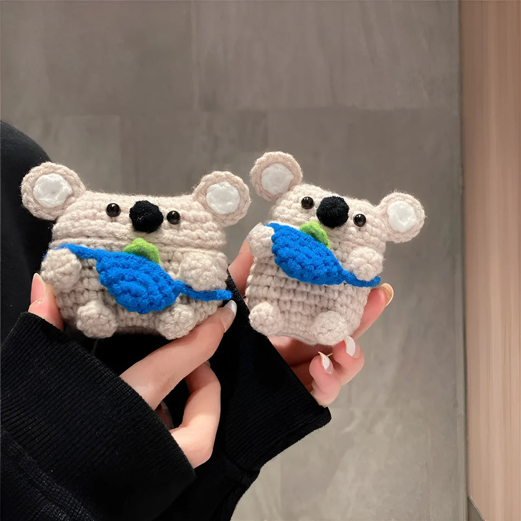 Handmade knitted koala bear backpack cover for AirPods charging case on a table.