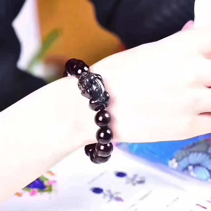 Natural ice colour eye obsidian crystal bracelet on a wrist, showing polished beads on an elasticated band.