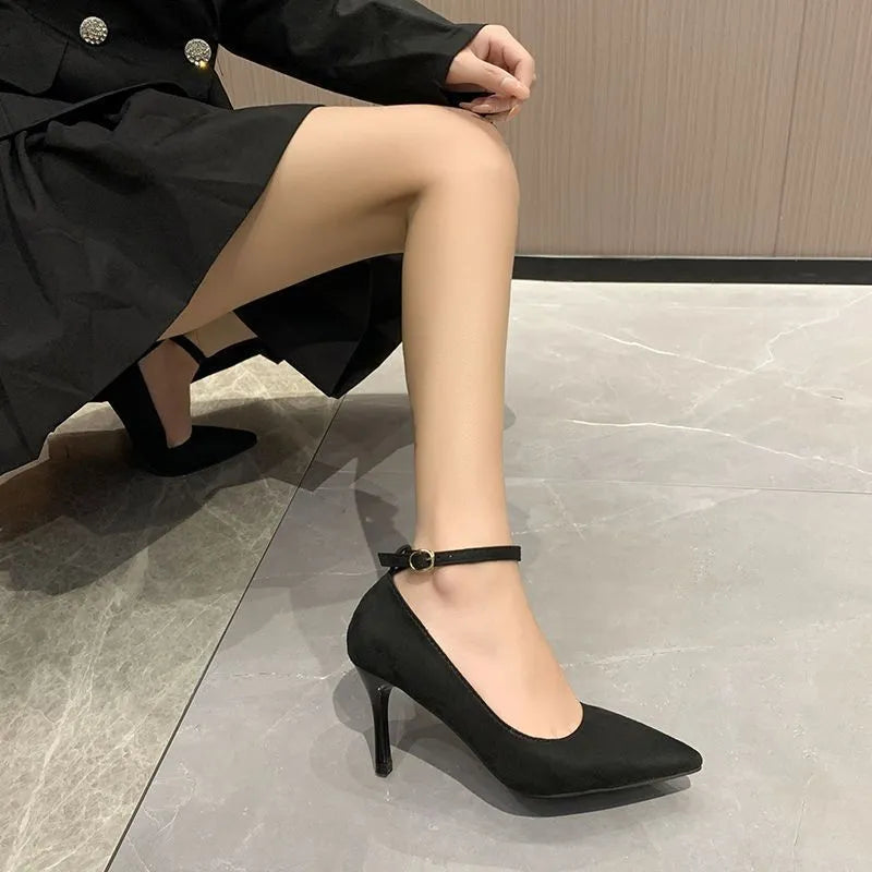 Women's black stiletto heel pump shoe with buckle detail on a white background.