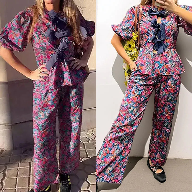 Women's floral print trouser suit set featuring a tie-neck blouse with puff sleeves and matching trousers.