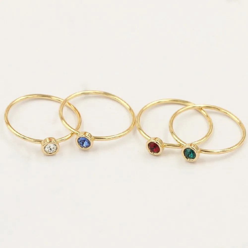 Women's copper knuckle ring with gilded finish and zircon stones in green, blue, red, and white.