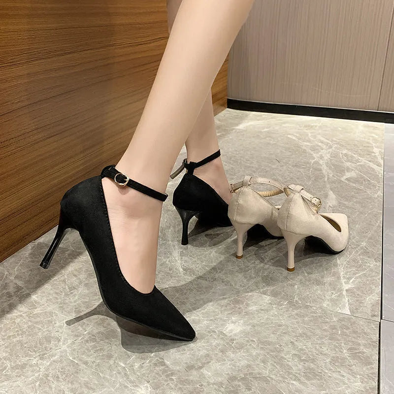 Women's black stiletto heel pump shoe with buckle detail on a white background.