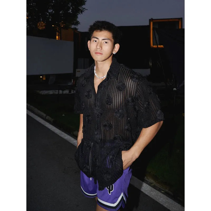 Man wearing a loose-fit black short-sleeved shirt with a large white three-dimensional floral print.