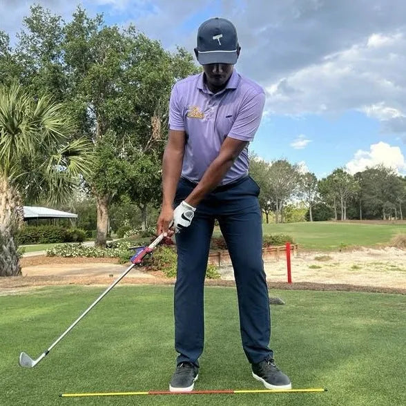 Plastic golf swing plane training simulator on a green background