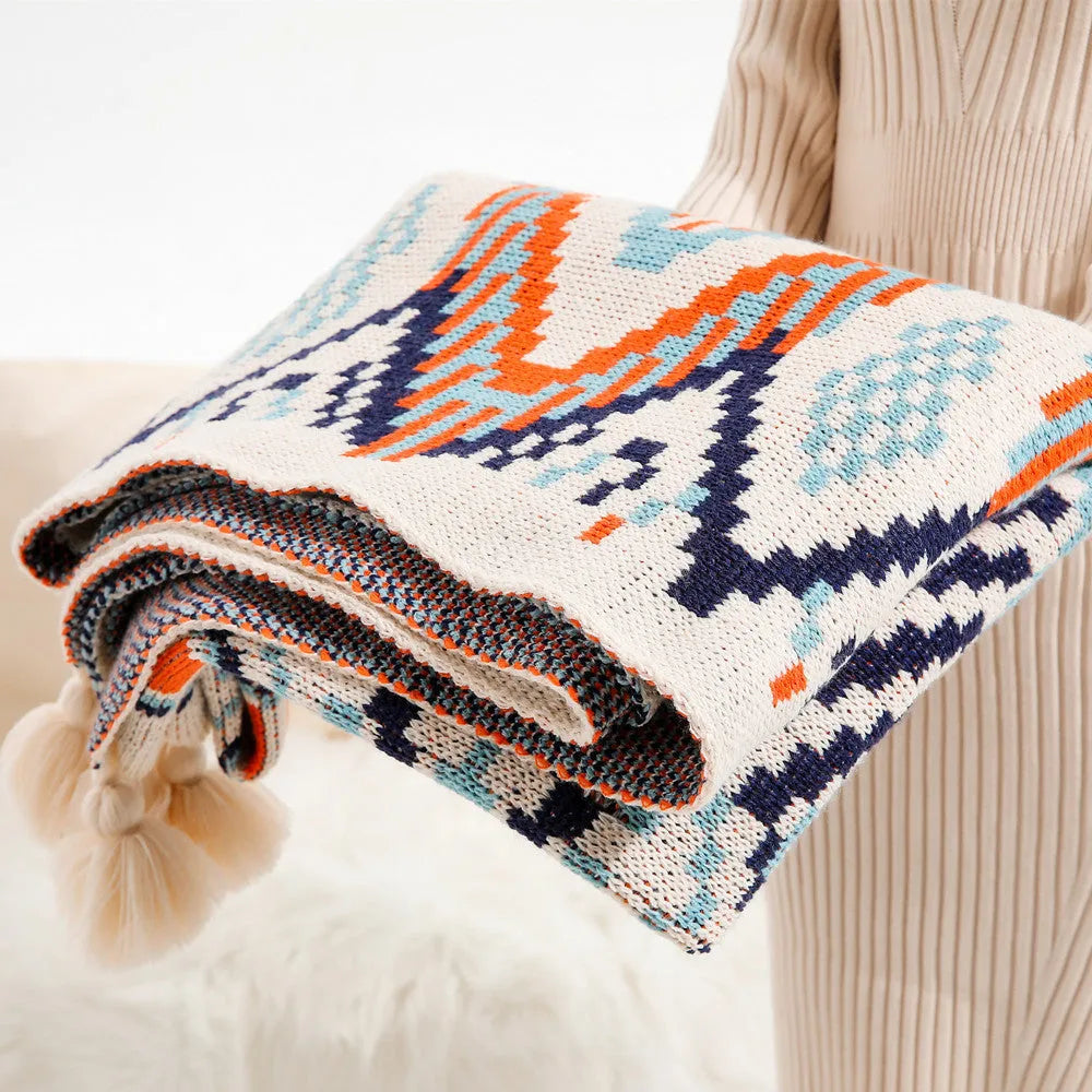 Acrylic sofa blanket with tassel fringe in neutral beige tone on grey sofa