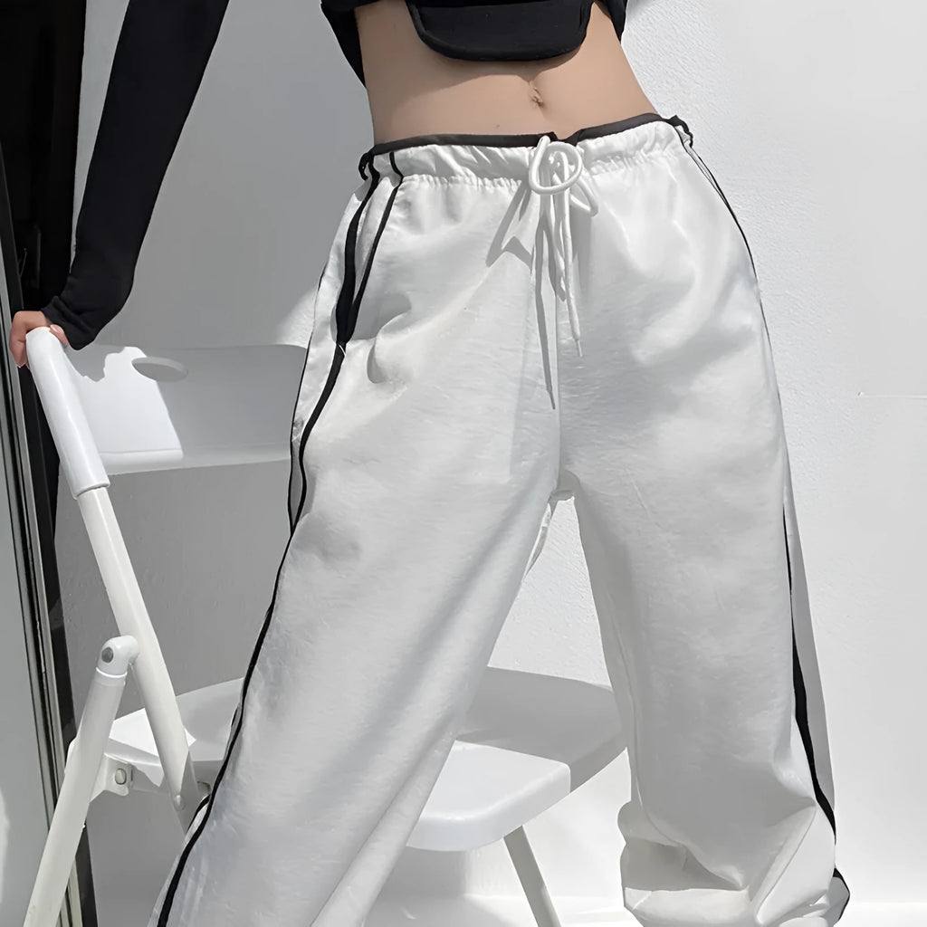 Women's navy blue loose straight-leg trousers with white contrast ribbon detail on parallel bars, low waist, draping silhouette