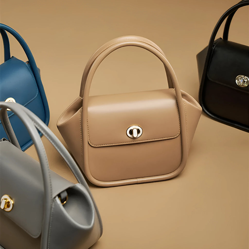 A wing-shaped women's leather tote bag with a buckle latch, shown in blue with a cross-body strap.