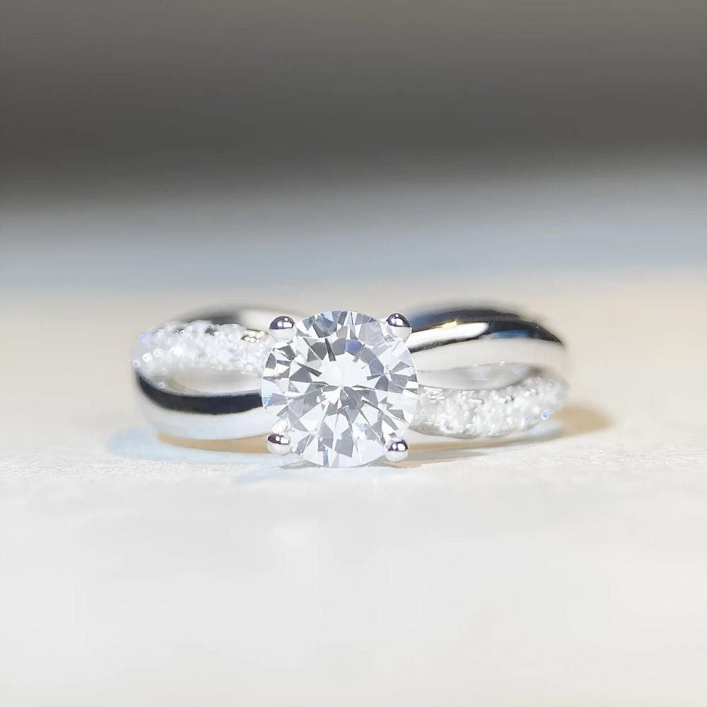 Women's geometric cross moissanite ring with twisted silver band and 1 carat stone.