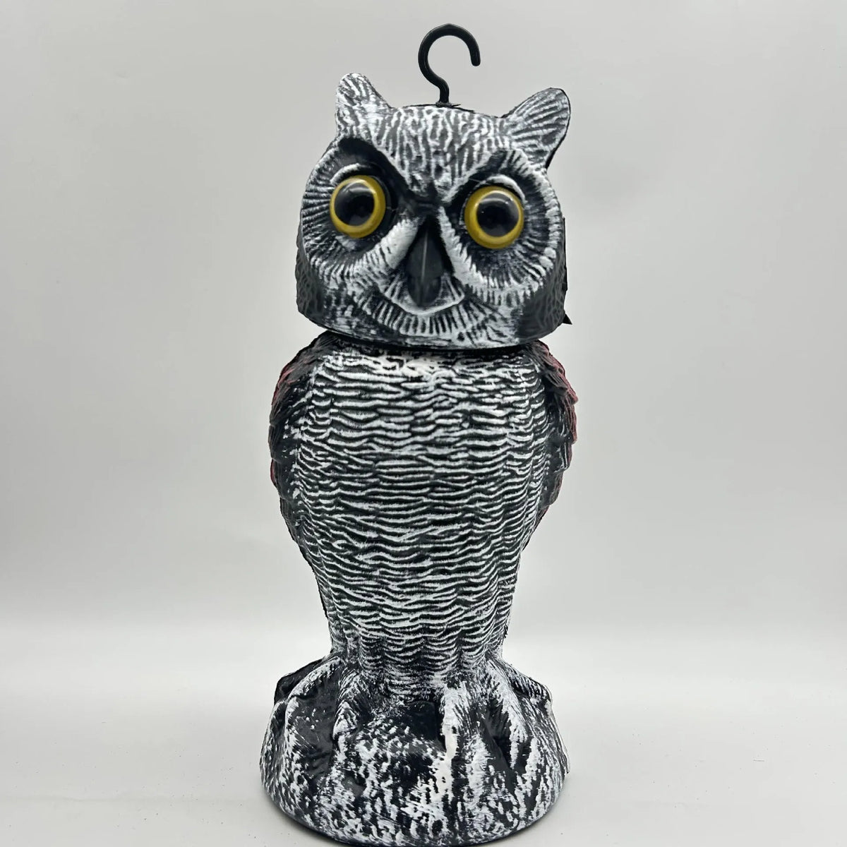 Polyethylene artificial owl bird scarer ornament with moving head, shown in a garden setting.