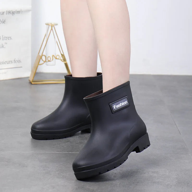 Women's mid-calf PVC rain boot in black on a wet surface