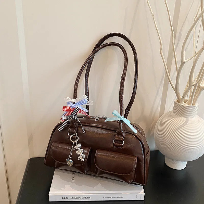 Brown retro-style women's PU leather pillow bag with flap and double strap, shown with ribbon pendant.