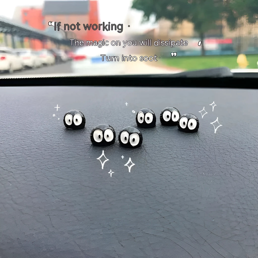 Small black resin coal ball cartoon decoration on a car dashboard.