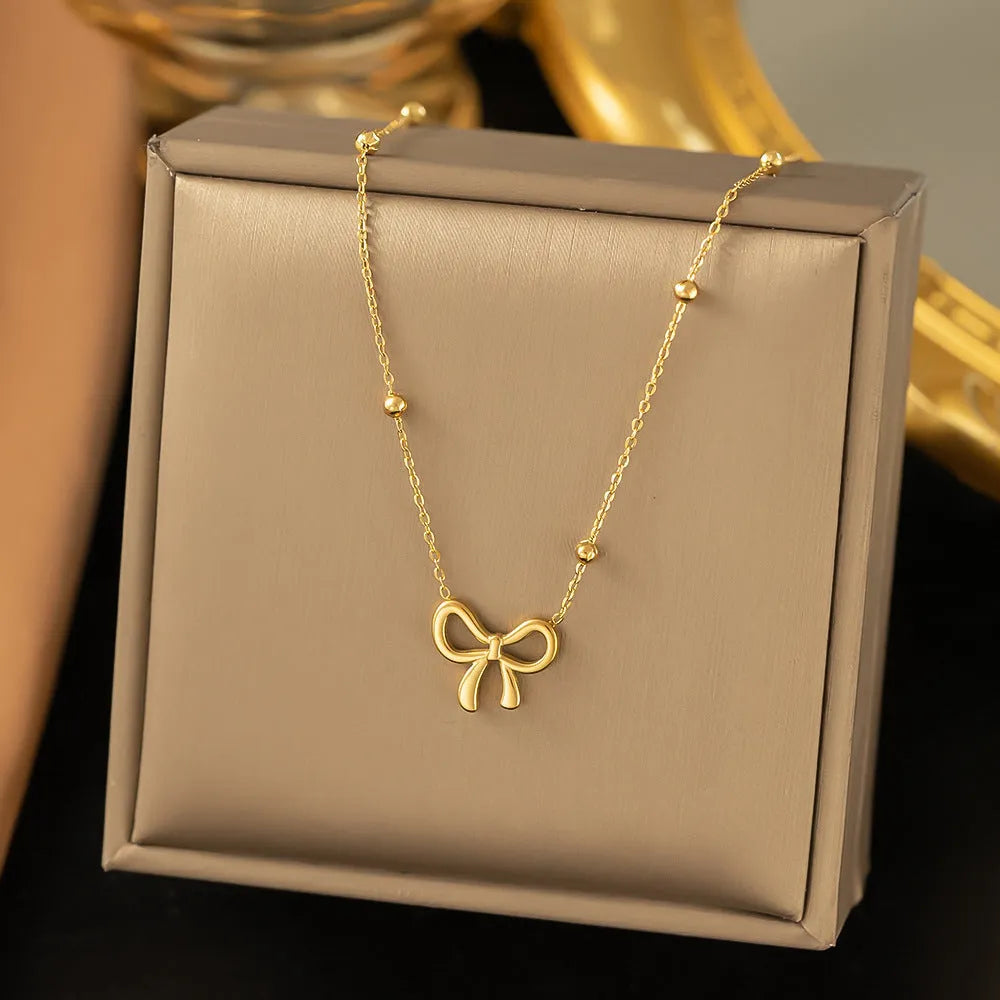Gold titanium steel bow necklace on a cross chain, adjustable between 41cm and 50cm.