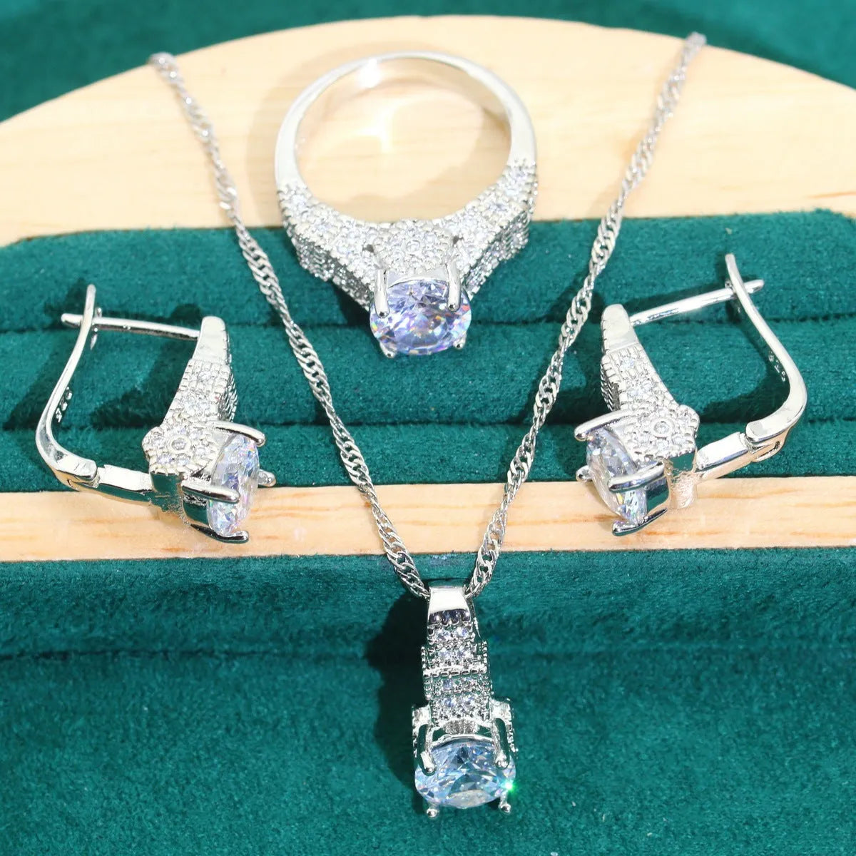Four-piece bridal jewellery set showing alloy pendant necklace, bracelet, earrings, and ring on a white background.