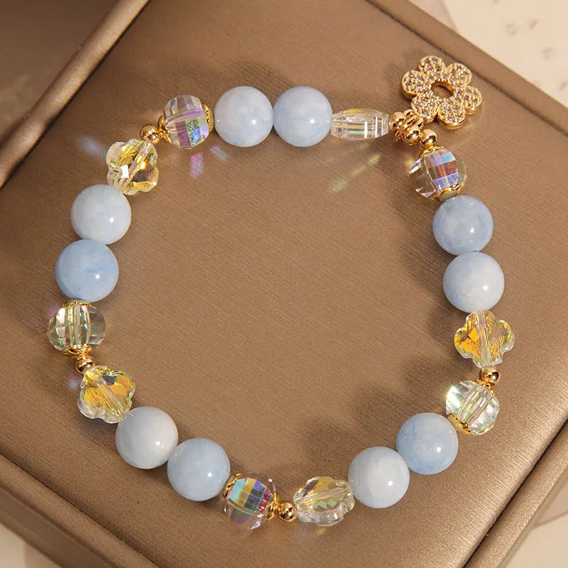 Women's adjustable bracelet with aquamarine crystal four-leaf clover charm and pearl detail.