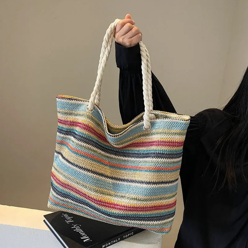 Blue woven straw and nylon shoulder bag with a large main compartment and zippered closure.
