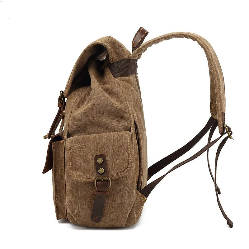 Retro canvas backpack in army green colour with antique bronze hardware, shown with a laptop to scale.