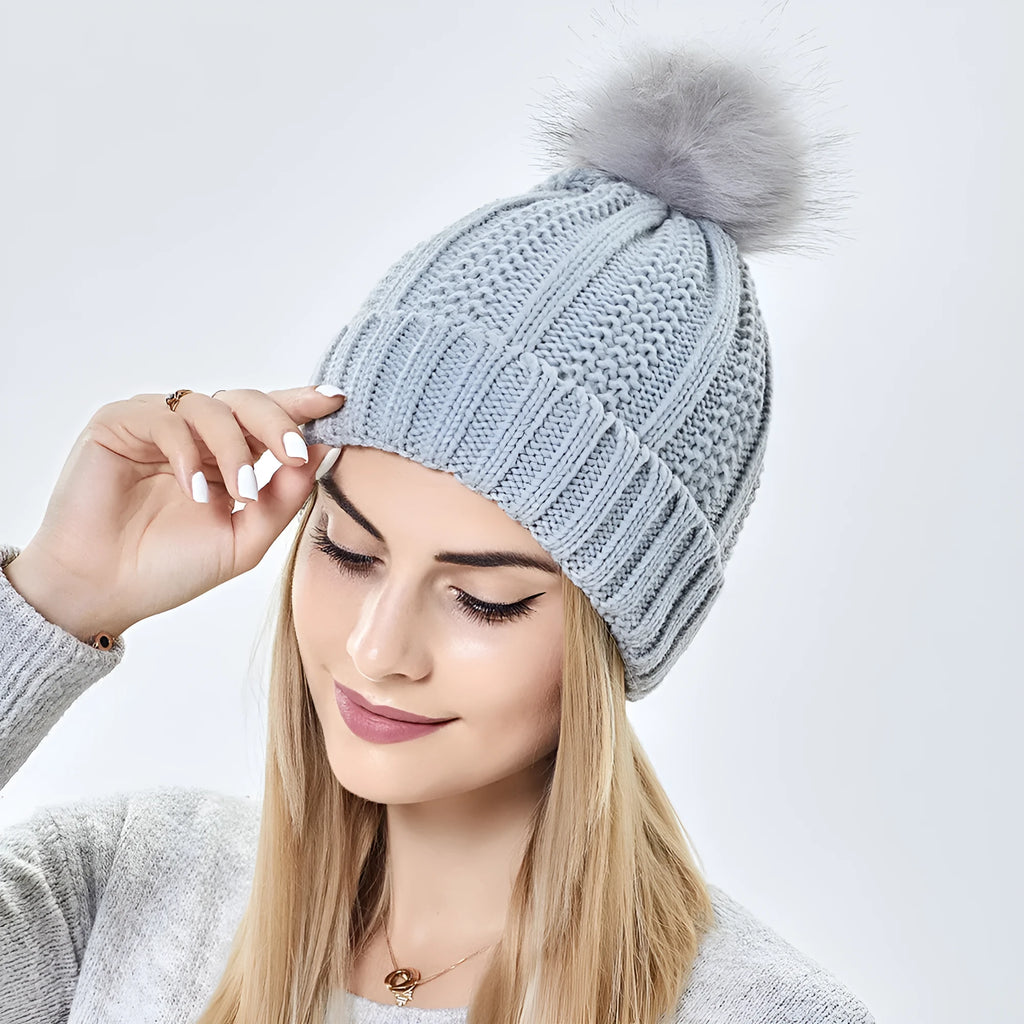 Wool beanie hat with faux fur pom pom, shown in black, with a visible satin lining.