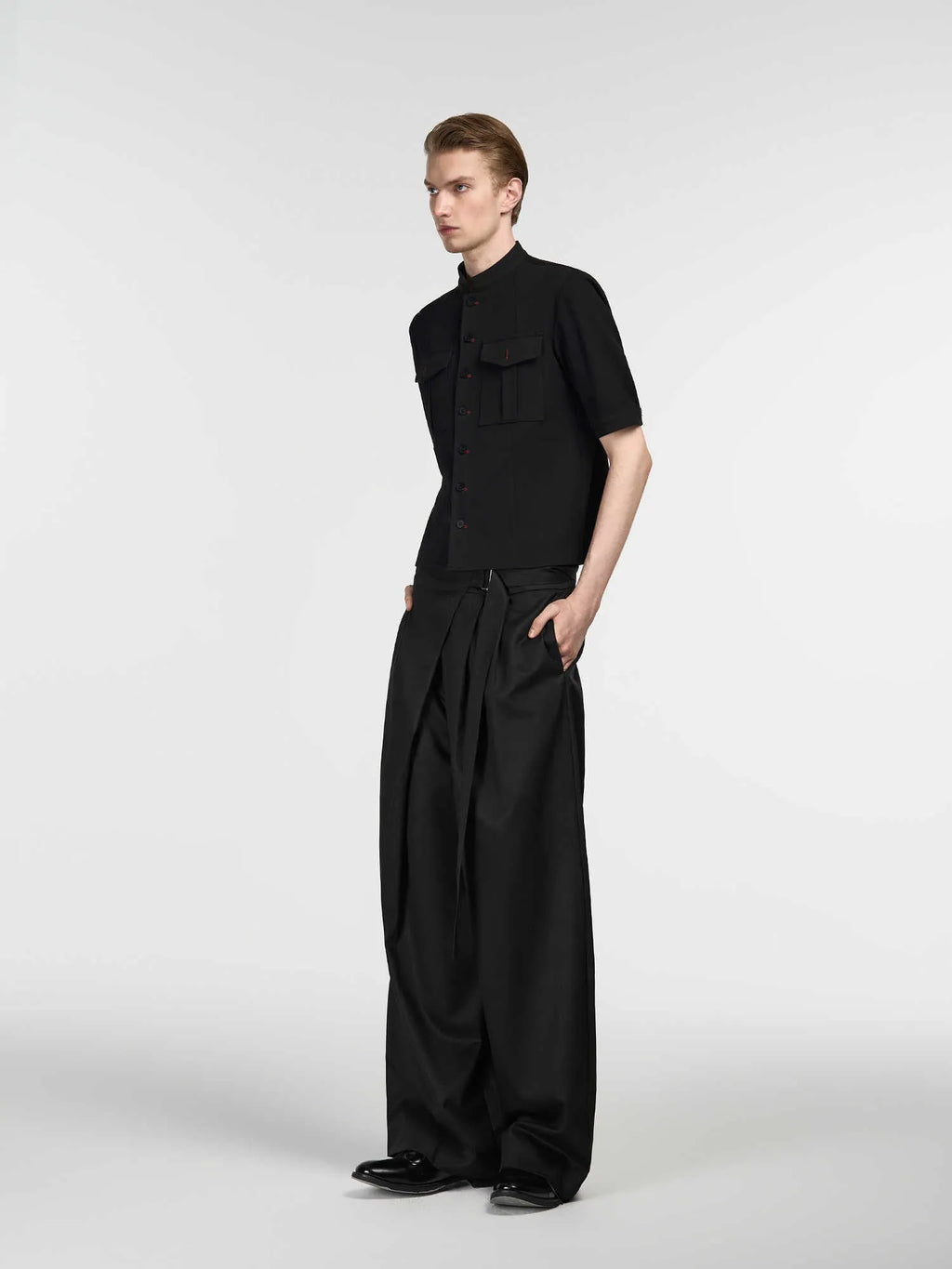 Black straight-leg trousers with a single pleat and adjustable waistband, laid flat.