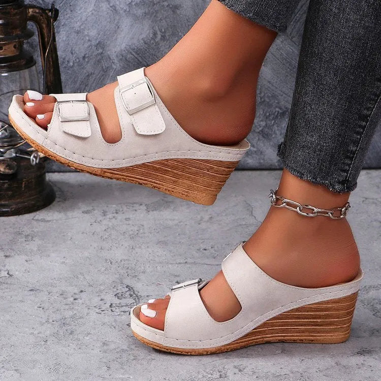 Women's creamy-white beach slippers with a wedge heel and an adjustable buckle strap across the foot.