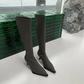 Black pointed toe below knee stiletto heel boots with a back zip, shown on a foot.