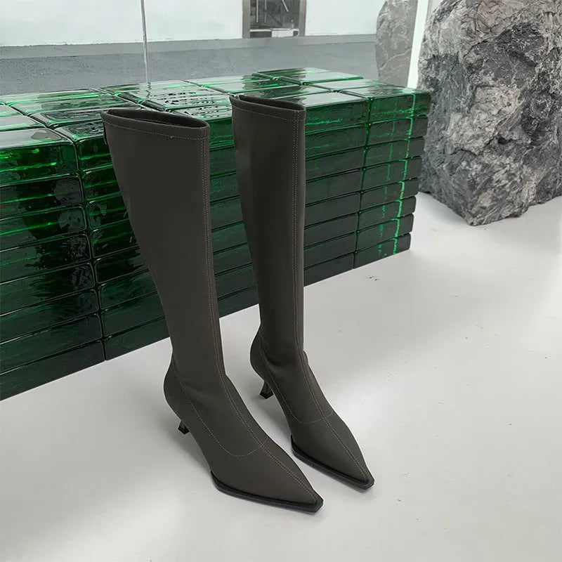 Black pointed toe below knee stiletto heel boots with a back zip, shown on a foot.