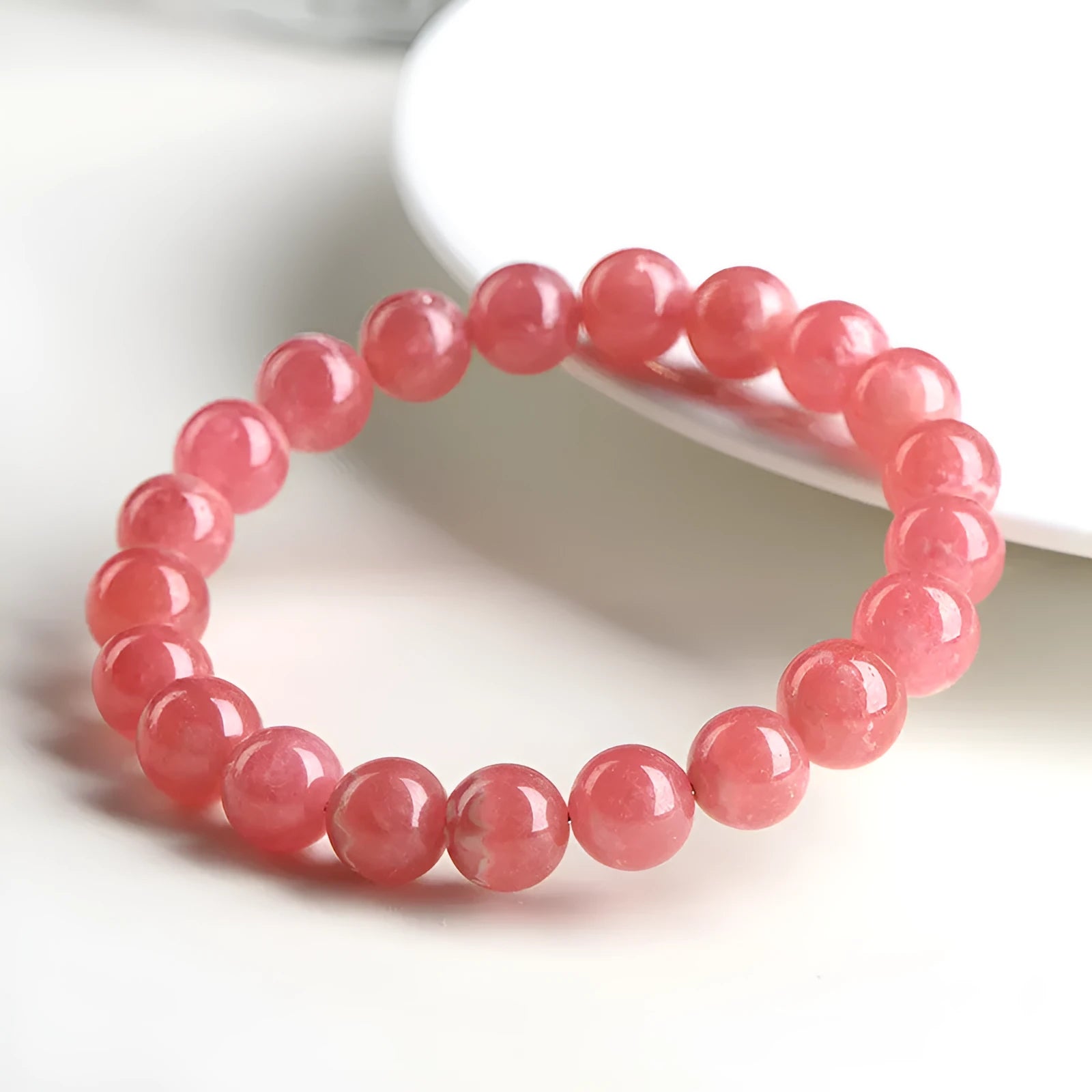 Women's geometric crystal bracelet with rhodochrosite pattern and a longevity lock charm.