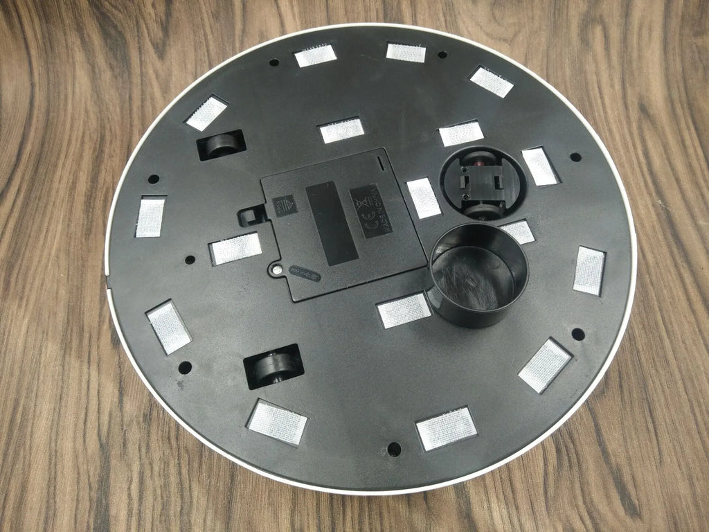 Black and white AC automatic sweeping robot cleaner on a hardwood floor.