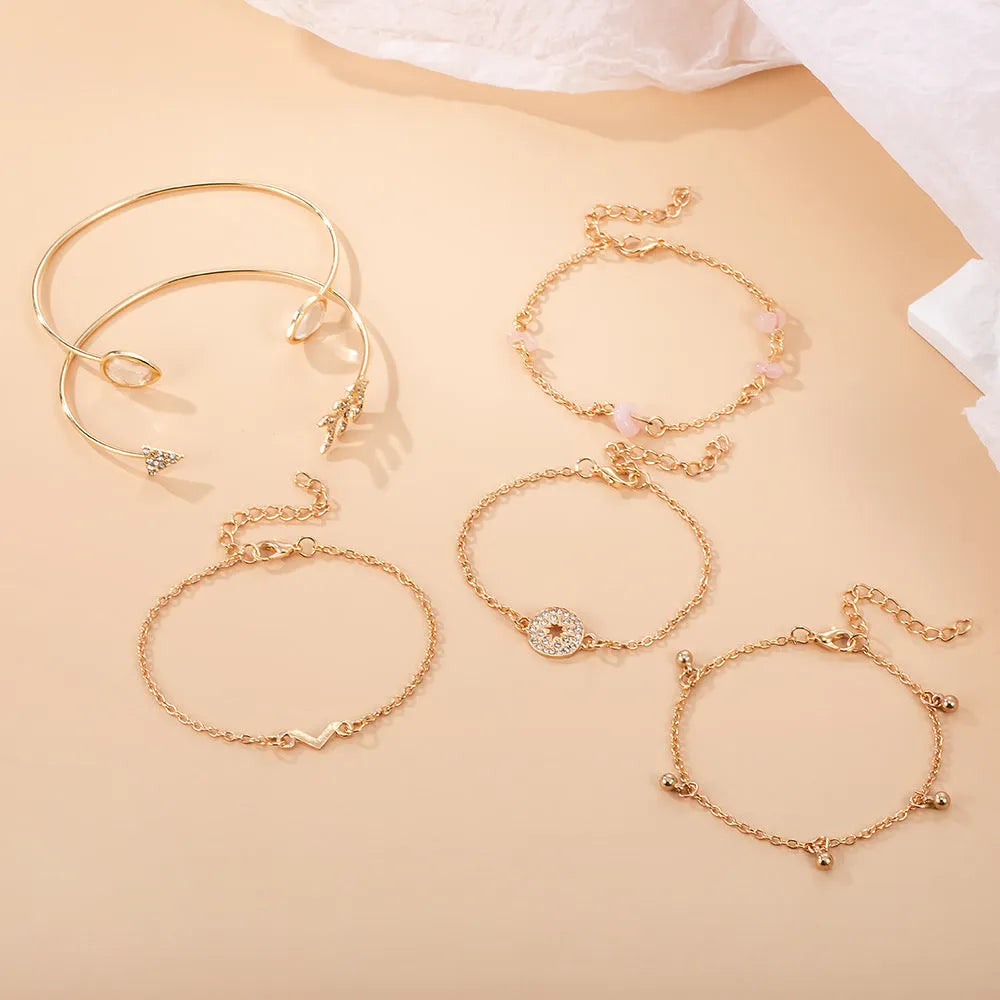 Set of six golden bracelets with arrow, water drop and V shapes featuring spot drill pattern.