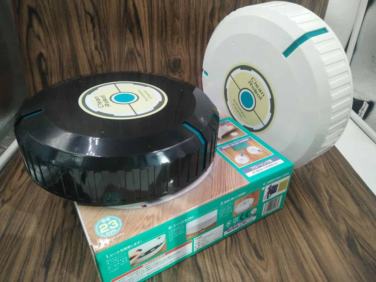 Black and white AC automatic sweeping robot cleaner on a hardwood floor.