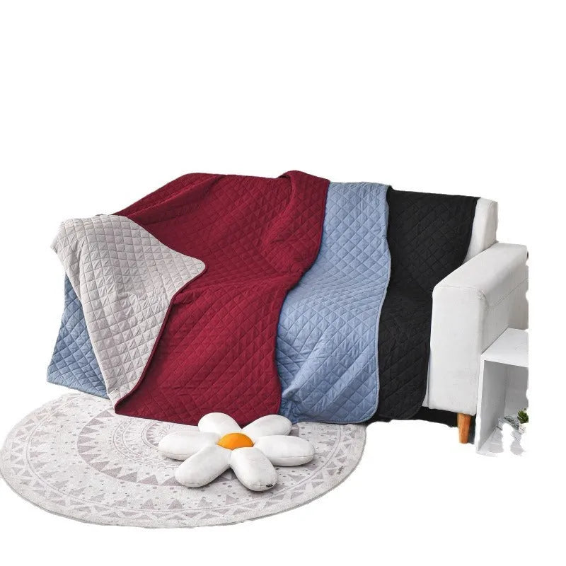 Waterproof reversible dog blanket on sofa showing two colour sides, protecting furniture from pet stains and hair