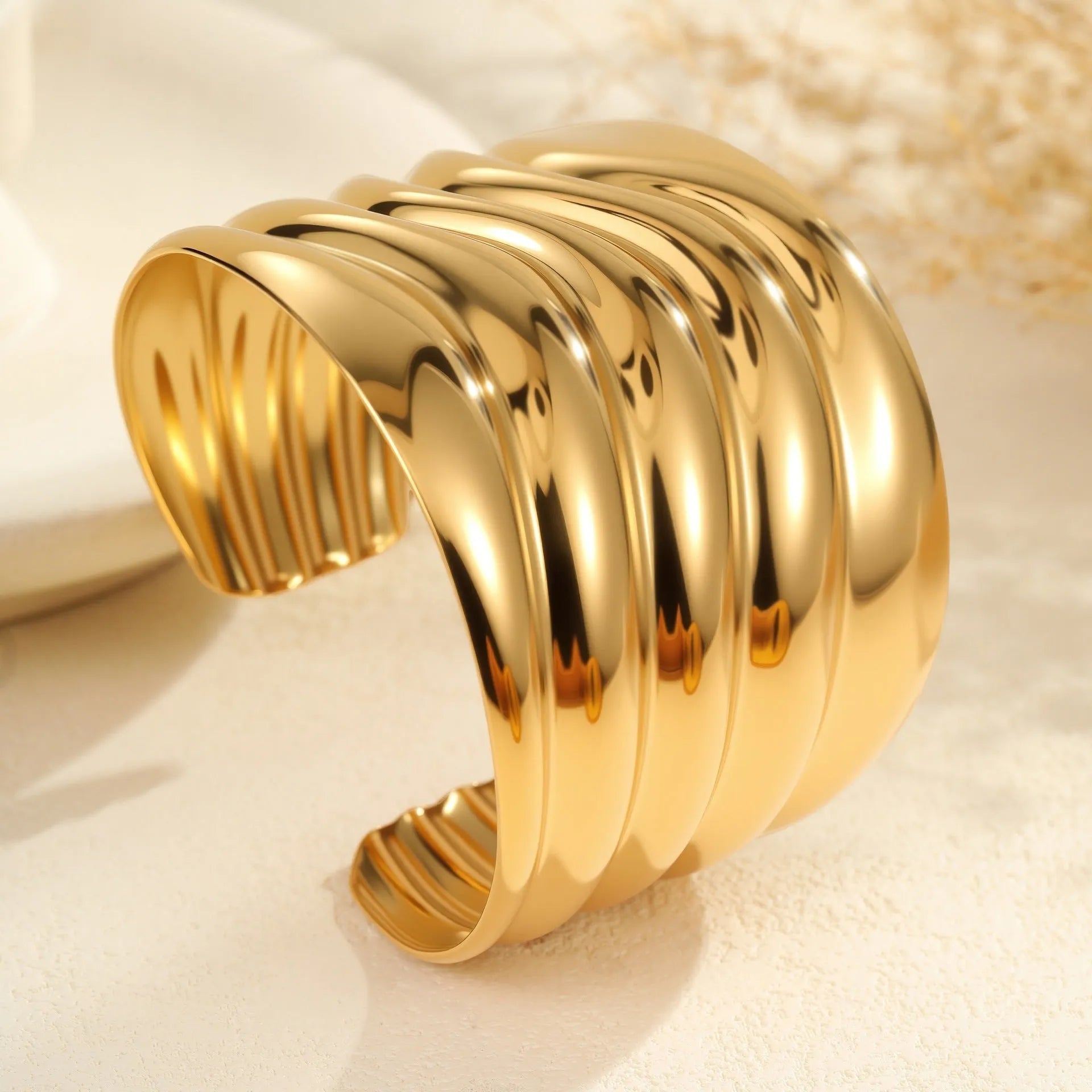 Gold-plated stainless steel wide bracelet with wave geometric design and a niche opening.