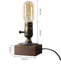 Compact wooden and iron water pipe table lamp on a table surface