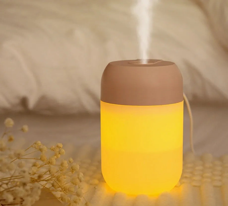 White cylindrical mini humidifier with USB cable on a desk