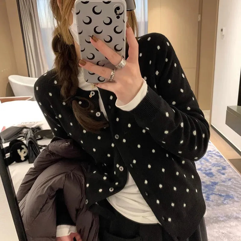 Women's grey dot patterned knitted cardigan with crochet flower detail on sleeve.