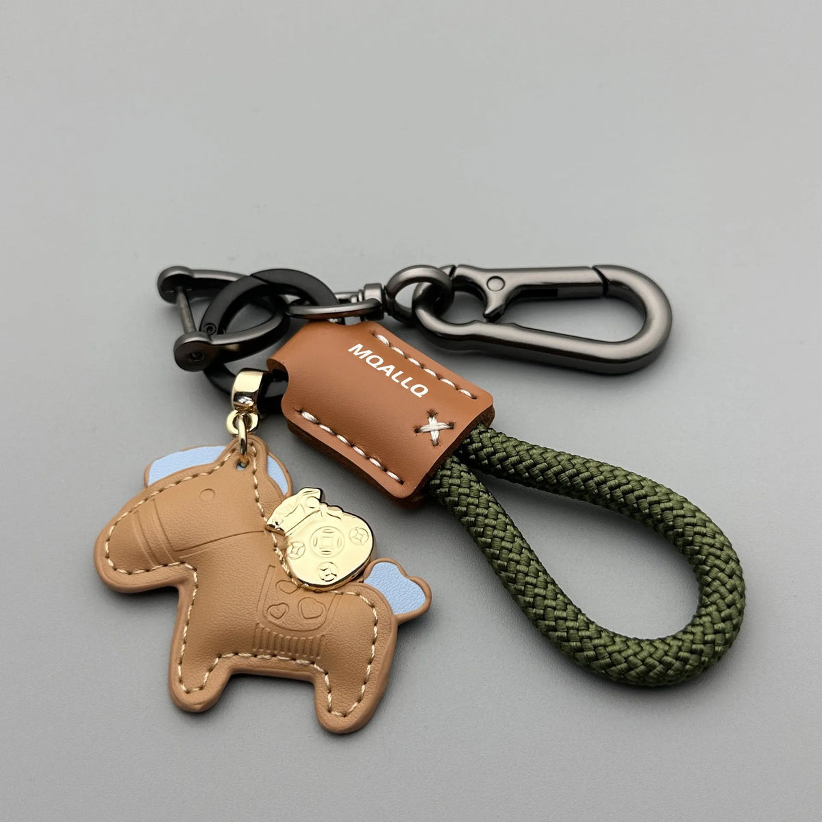 Handmade brown cowhide leather key ring with a gold-toned zinc alloy pony buckle and a green plaited flannelette rope.