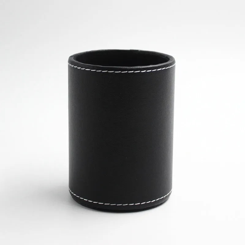 Small round black leather pen holder container on a desk