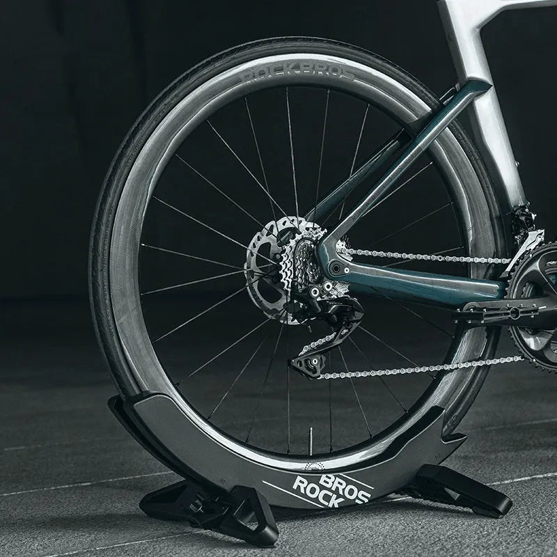 Black and green ABS plastic bicycle parking rack holder mounted on a wall.