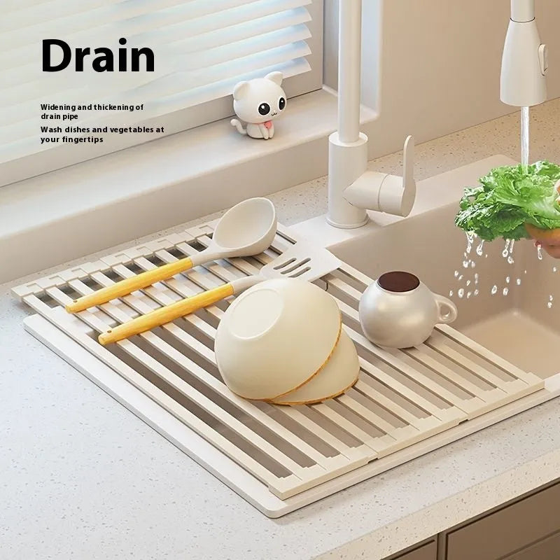 Milky white foldable stainless steel kitchen draining rack shown unfolded next to a sink.